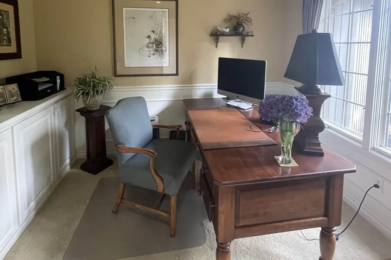 Home office with a cherry wood desk, white built-in cabinets and tall windows, from a Sammamish remodel by Volcano Builders