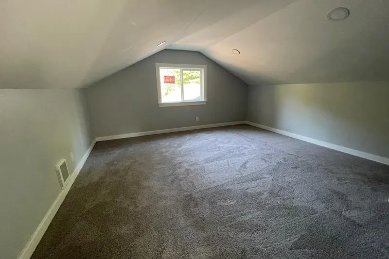 Finished attic room with a gable window and new carpet, from a Kirkland attic remodel by Volcano Builders