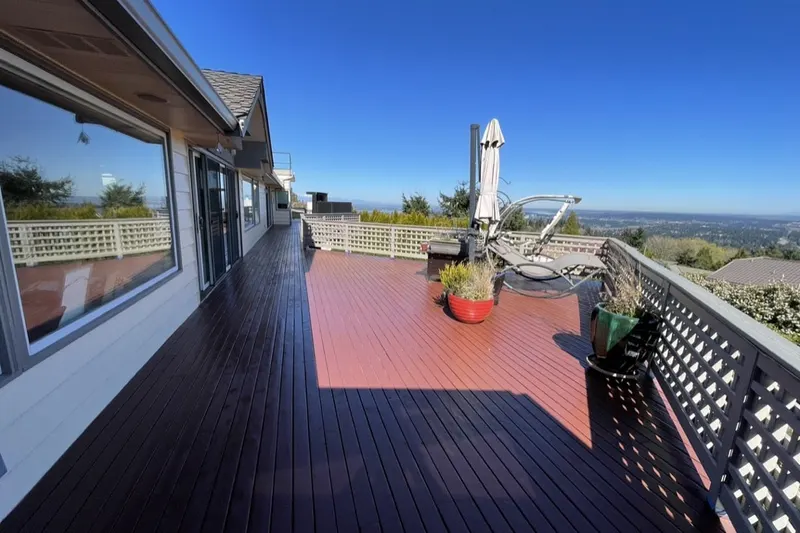 Refinished wraparound deck with two tone boards and white lattice railing on a Bellevue hillside home, a Volcano Builders project