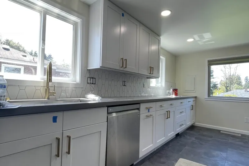 Remodeled kitchen with white shaker cabinets, dark counters and a hexagon tile backsplash, a Tukwila project by Volcano Builders