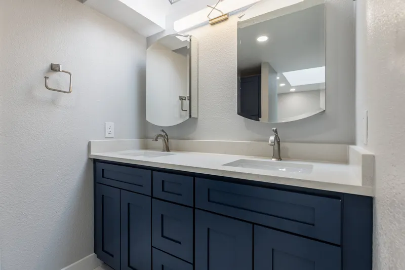 Navy double vanity with a white quartz top and two mirrors, from a Redmond bathroom remodel by Volcano Builders