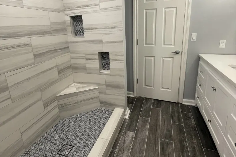 Tiled shower with a bench and niches in a Federal Way basement remodel by Volcano Builders