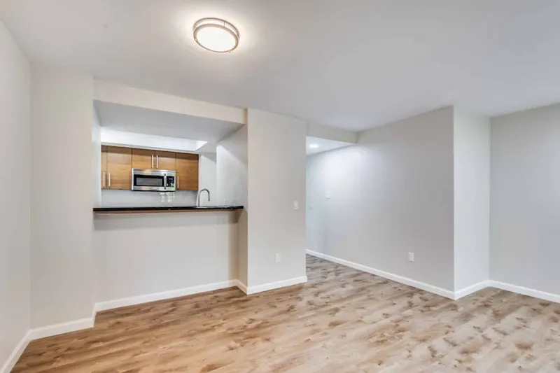 Finished living area with new plank flooring and a pass-through kitchen with wood cabinets and a dark granite bar, from a Renton remodel by Volcano Builders