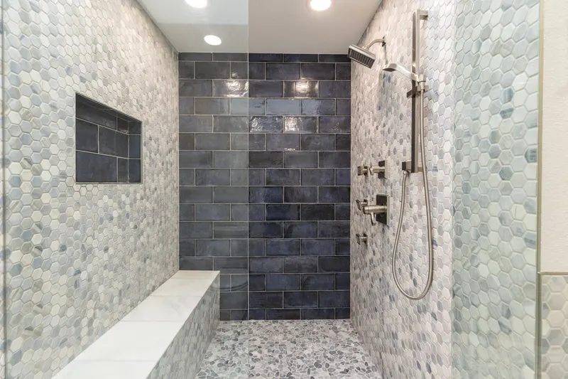 Walk-in shower with a tiled bench, hex mosaic walls and navy subway tile, from a Redmond bathroom remodel by Volcano Builders