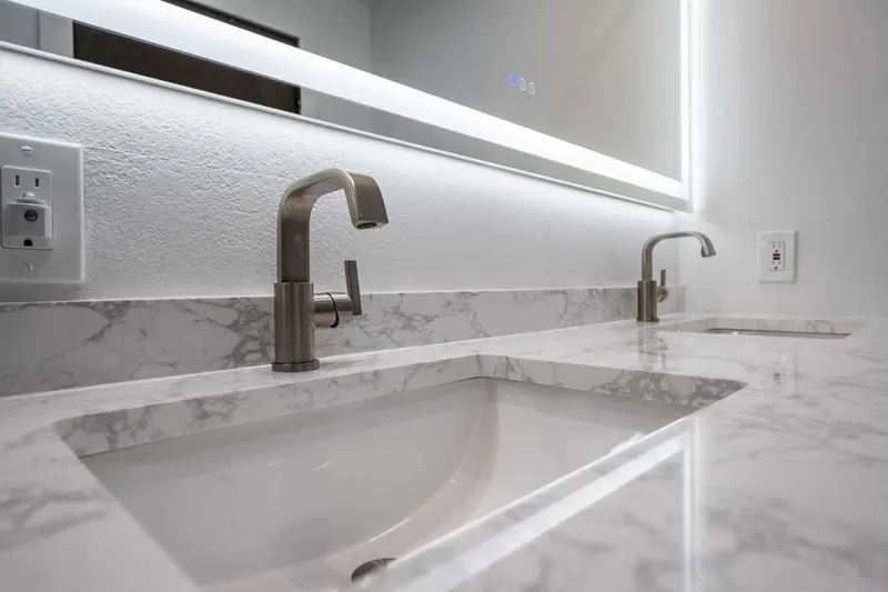Marble-look double vanity top with undermount sinks, brushed nickel faucets and a backlit mirror from a Tulalip Bay bathroom remodel by Volcano Builders
