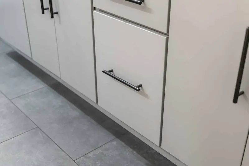 Light gray flat-panel vanity with matte black bar pulls above a large-format gray tile floor, from a Kirkland bathroom remodel by Volcano Builders