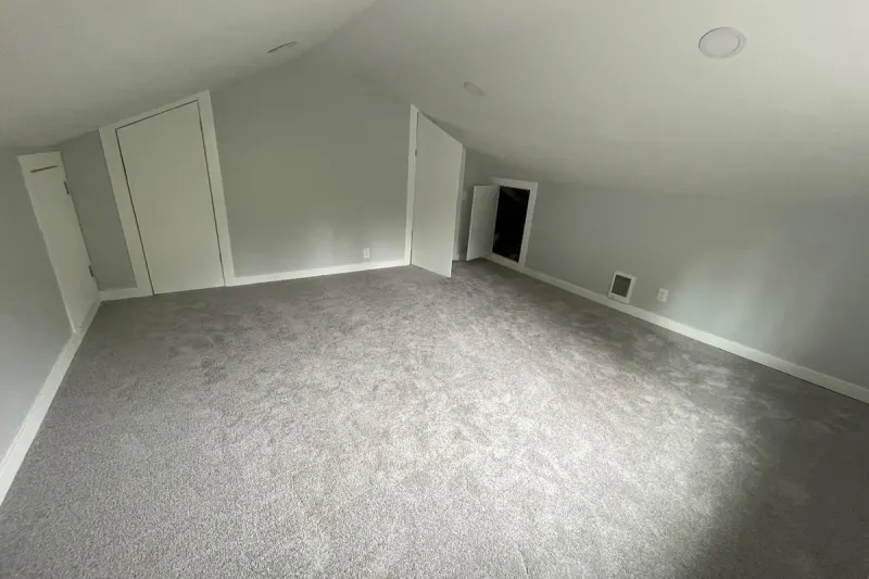 Finished attic room with new gray carpet, sloped ceilings and built-in closet doors, from a Kirkland attic remodel by Volcano Builders
