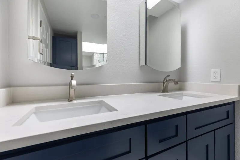 Navy shaker double vanity with a white quartz top and two undermount sinks, from a Redmond bathroom remodel by Volcano Builders