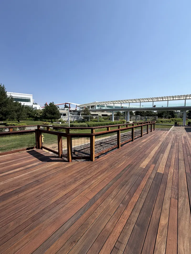 Refinished deck corner with wood and wire railing overlooking a lawn