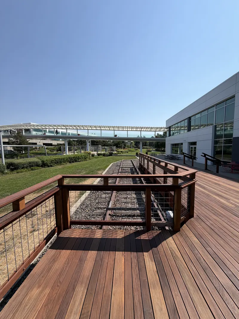 Refinished deck with a railing bay overlooking the preserved rail line, office building on the right