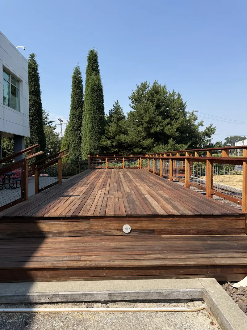 Refinished raised deck platform with a step light in the riser, cypress trees and the building behind