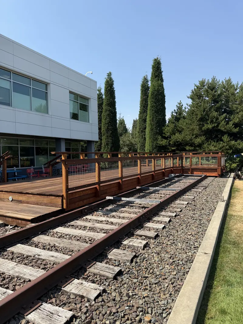 Refinished deck railing running along the rail line, viewed down the track