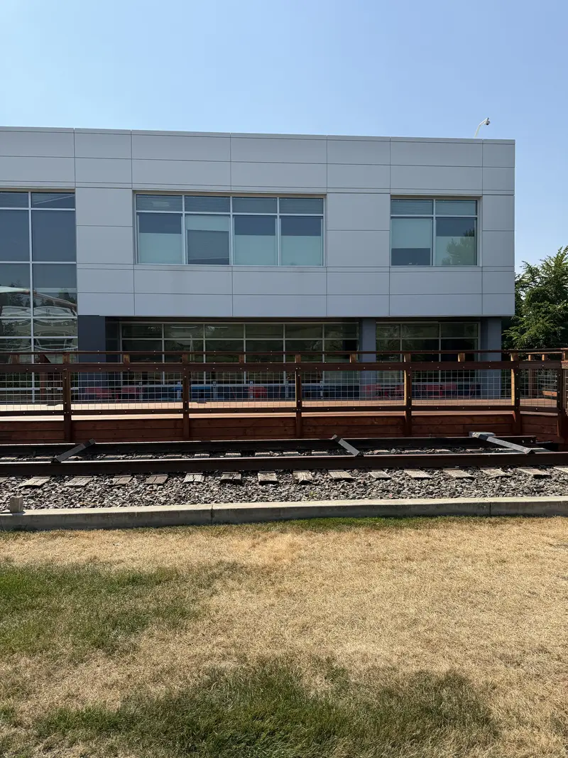 Refinished deck and railing seen from the lawn across the rail bed, office building behind