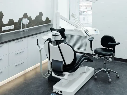 Empty dental operatory with a black and white patient chair, delivery unit, operator stool and white cabinetry