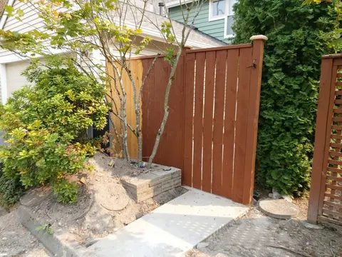 Concrete walkway leading to a new stained wood fence gate in Redmond, WA
