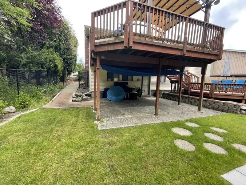 Old exposed aggregate patio under an upper deck, with stepping stones in the lawn