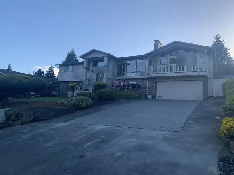 Wide view of the new concrete driveway from the street, with the house, garage and landscaping