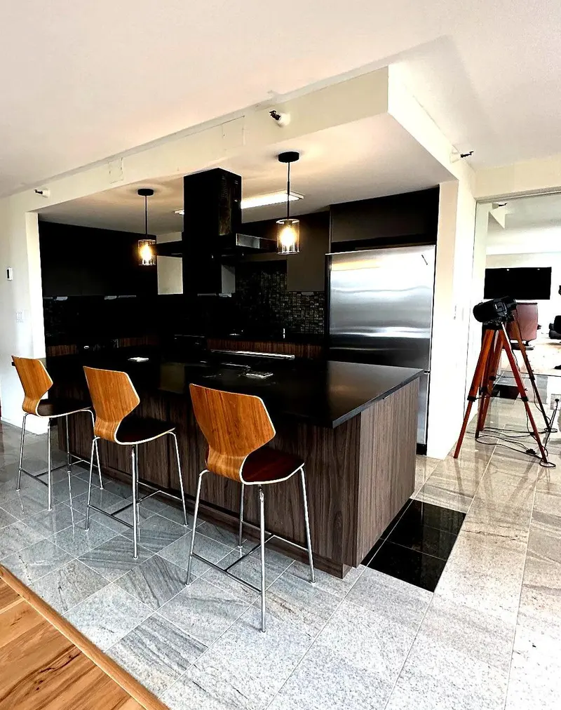Kitchen island with three bar stools on the original gray stone tile floor