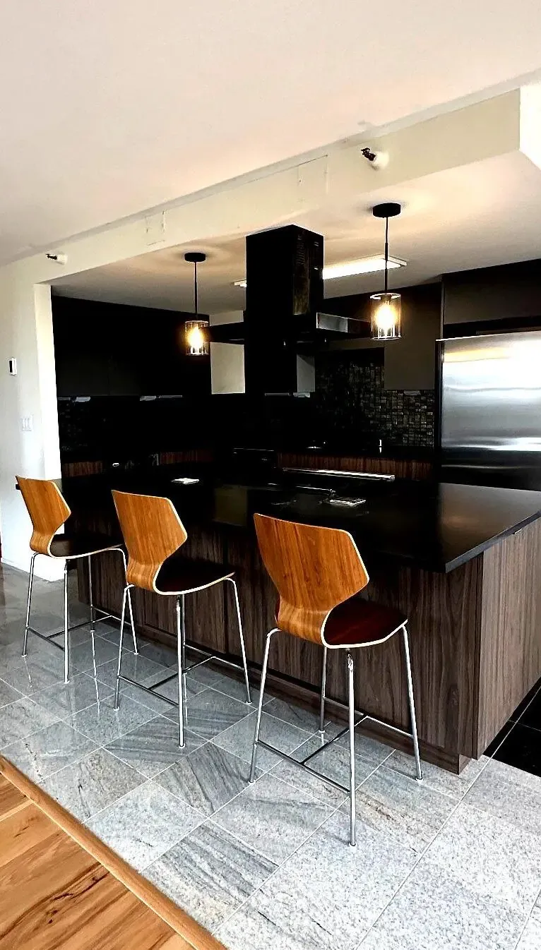 Kitchen island with three bar stools on the original gray stone tile floor