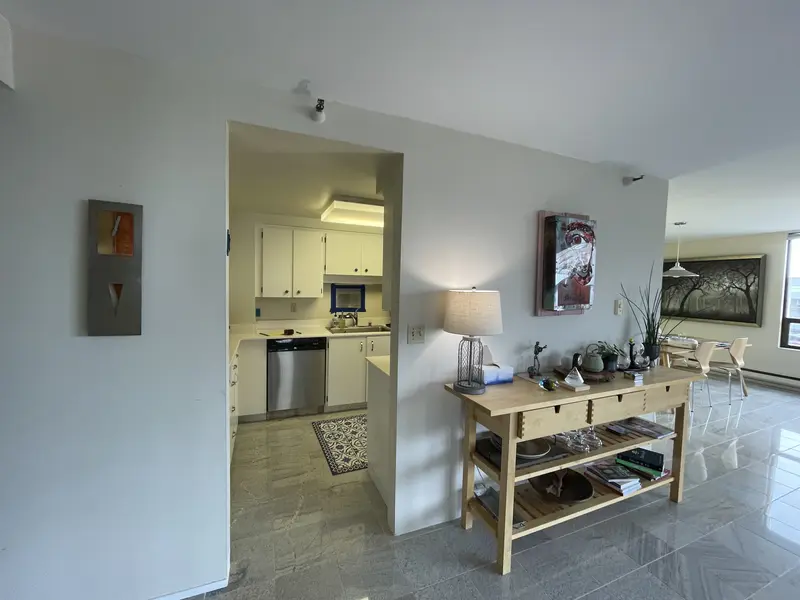 Wall with a narrow doorway into the galley kitchen, seen from the living room with stone tile underfoot