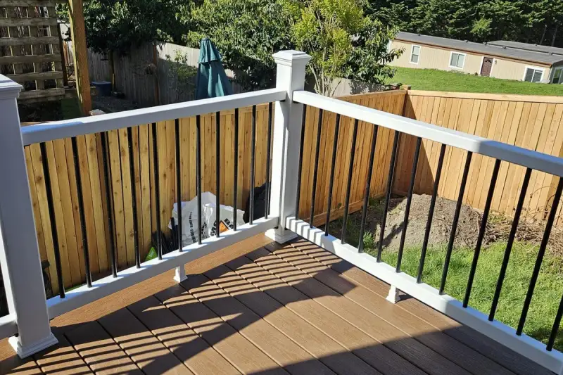 Composite deck with white railing posts and black balusters beside a cedar fence in Seattle, WA
