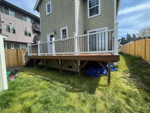 Raised composite deck with white railings on wood posts above a lawn in Seattle, WA