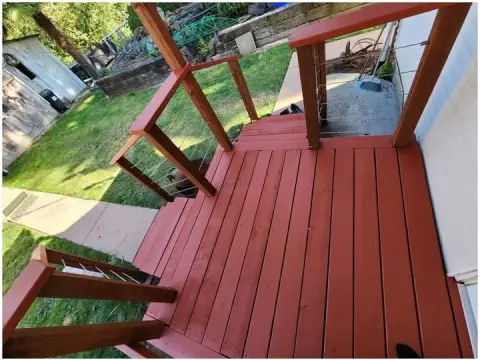 Porch deck and railings stained red beside a side yard in Seattle, WA