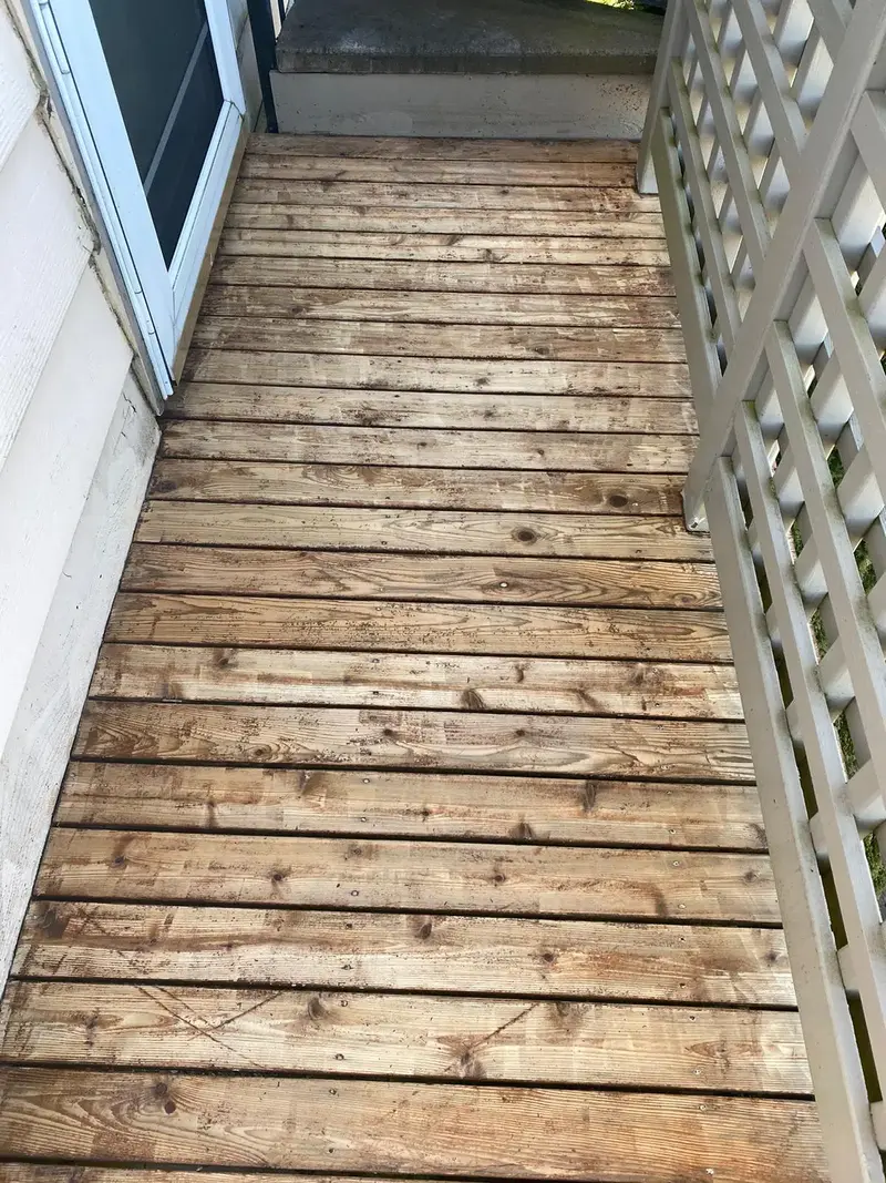 Narrow deck walkway with gray weathered boards between the house and a white lattice railing