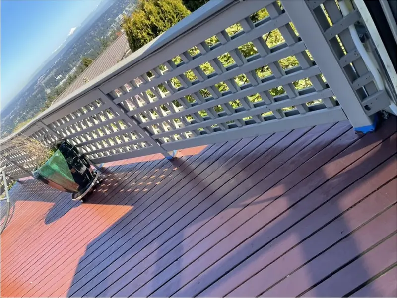 Stained deck boards meeting the white lattice railing at a corner, with a planter