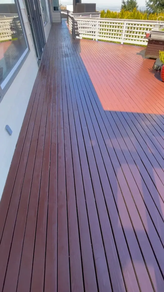 Full length of the stained deck walkway, shaded near the house and lit by sun at the far end