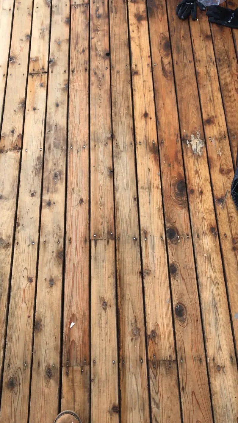 Close view of weathered deck boards with gray patches and dark stains