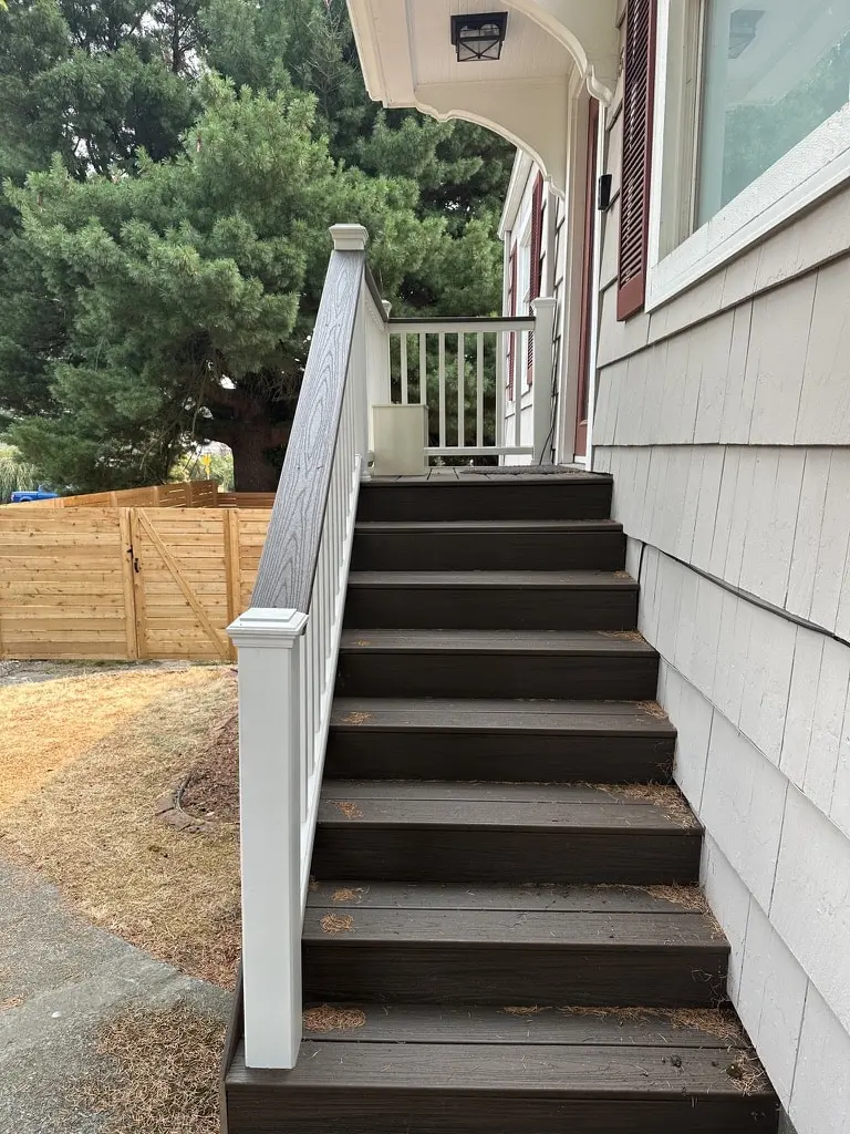 Straight stair with dark brown treads and white railings leading up to an entry