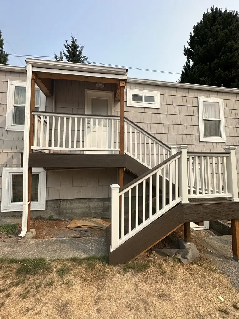 Side view of a raised landing under a small roof with a long stair along the house
