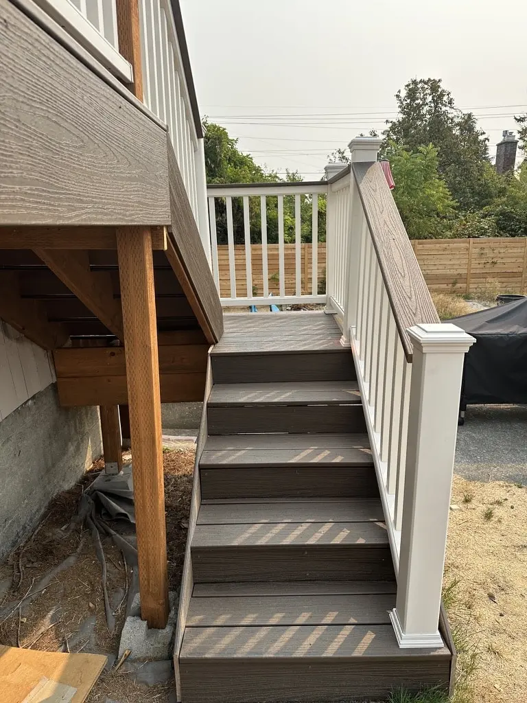Stair with dark brown treads and a white railing running down beside the wood support posts