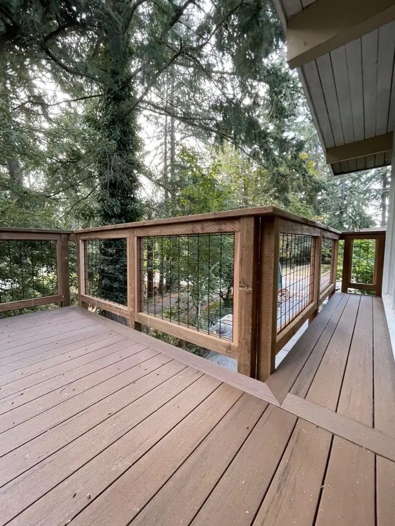 Corner of the new deck railing with a stained wood frame and black metal infill