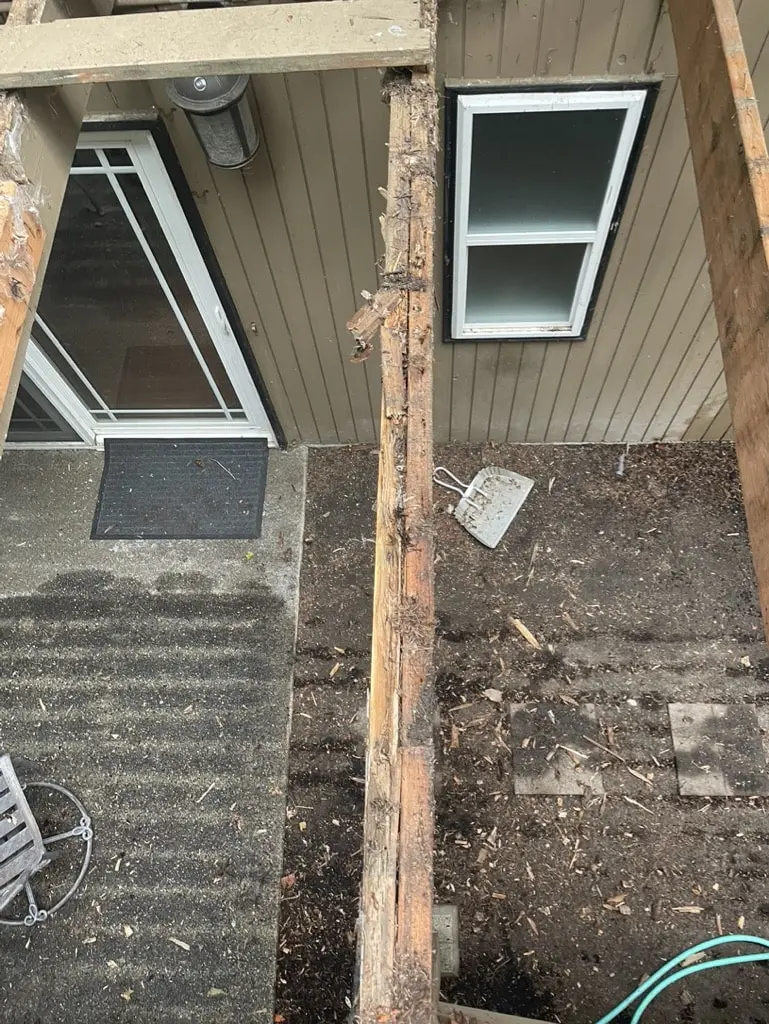 Rotted wood post beside a lower level door and window under the old deck