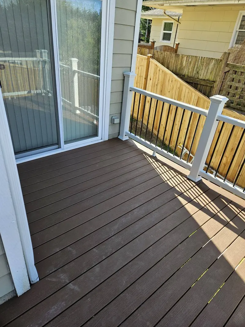 Deck boards outside a sliding glass door with the railing alongside