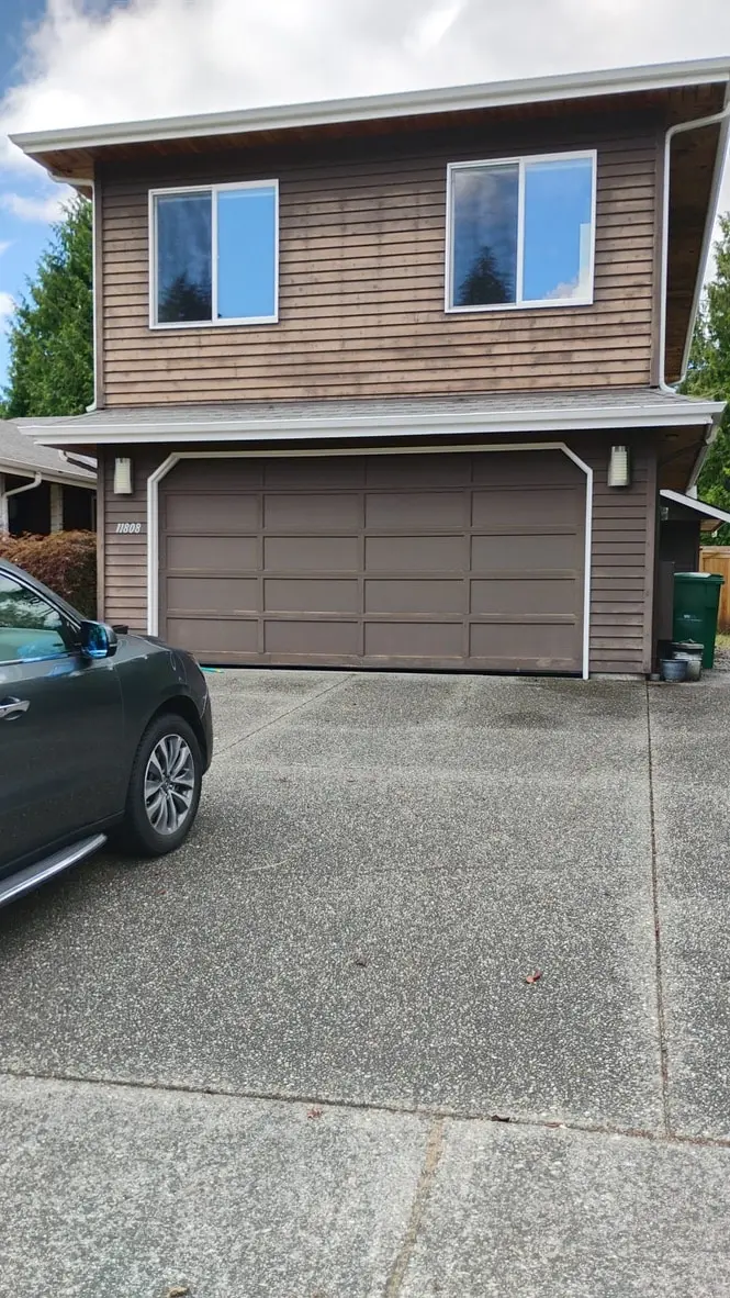 Brown two-story garage wall with a brown garage door and two upper windows