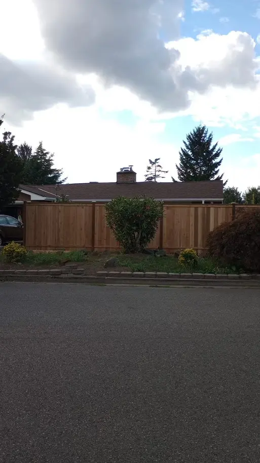Wood privacy fence across the back of a lot, seen across a paved driveway