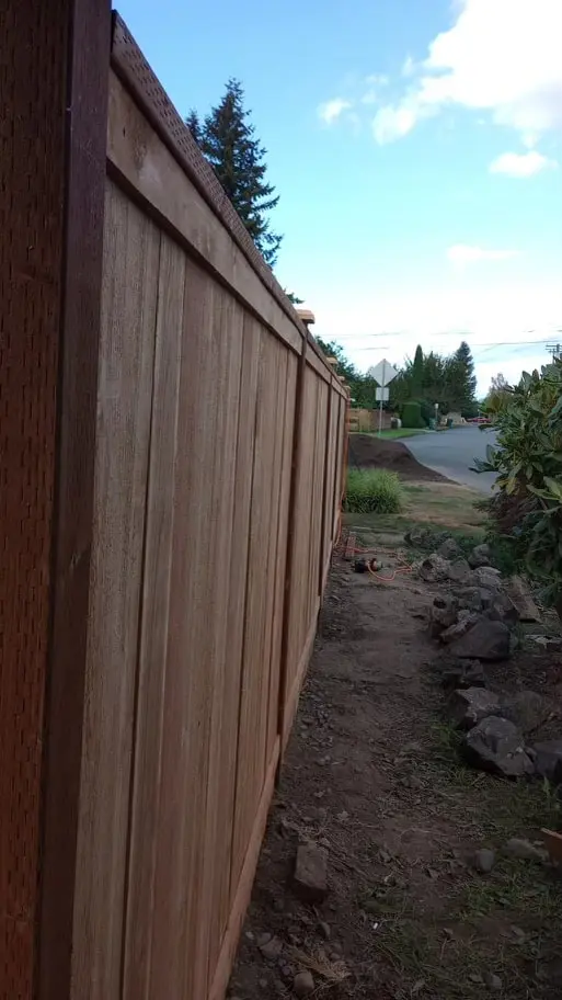 Side run of wood privacy fence with a darker top cap running its length