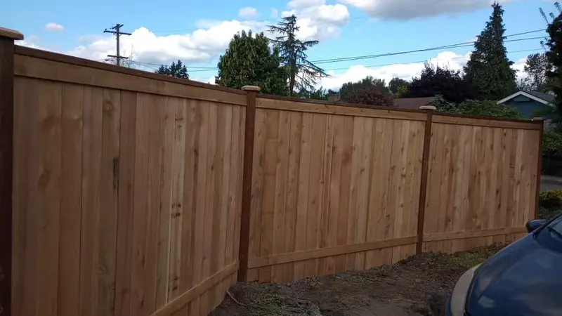 Long run of tall wood privacy fence under a blue sky
