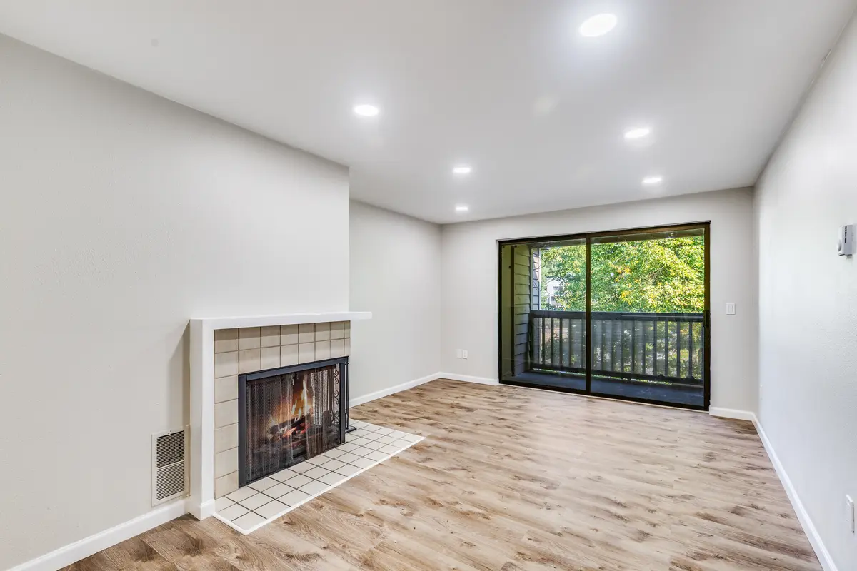 Empty condo living room with light wood-look vinyl plank floor meeting a tiled fireplace hearth
