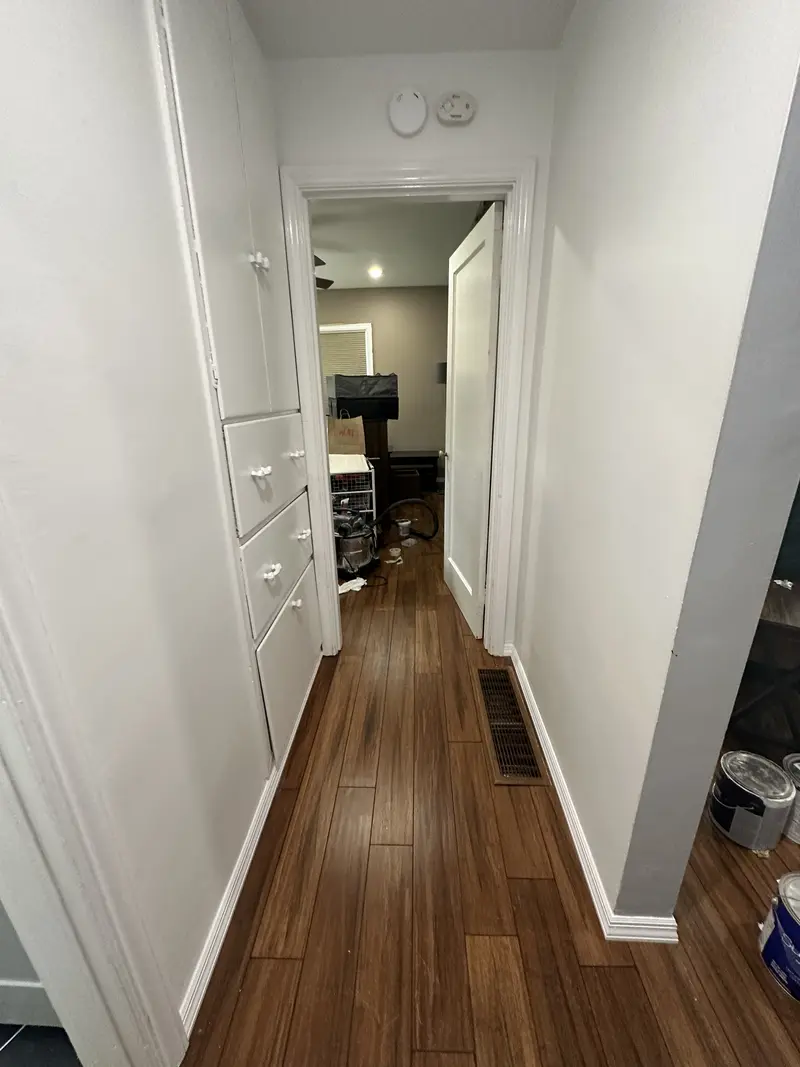 Narrow hallway with the plank floor running between white doors and trim