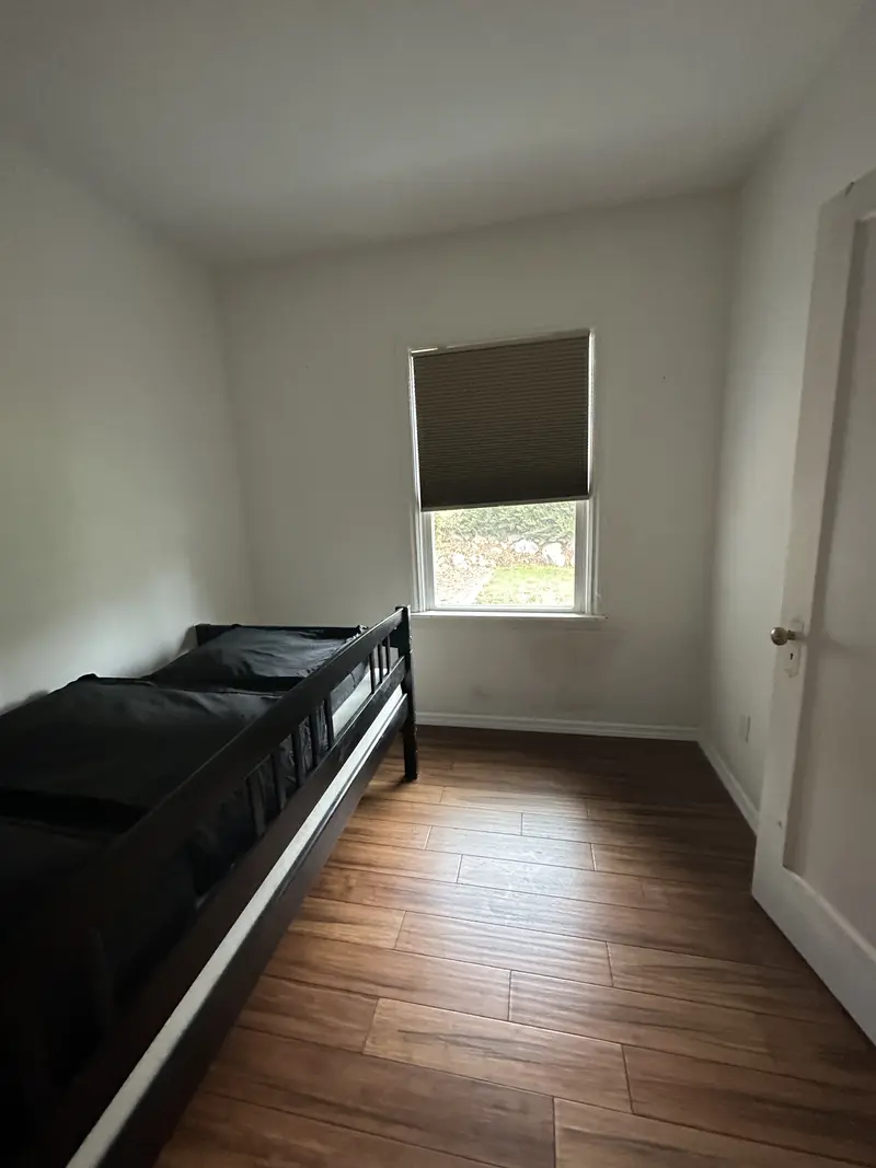 Small bedroom with the plank floor, a window and a daybed