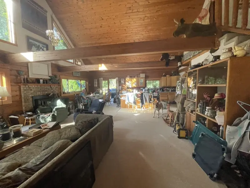 Log home great room with worn carpet and furniture before the flooring was replaced