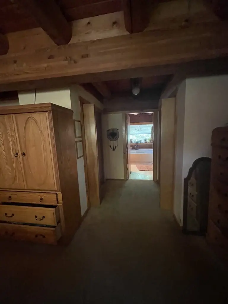 Hallway and log-walled entry before new flooring, with a wooden armoire