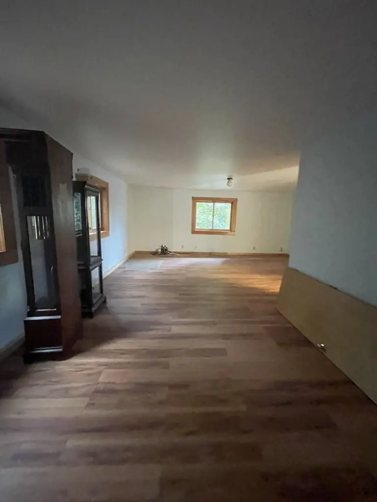Long room with a continuous wood-look plank floor and a window at the far end