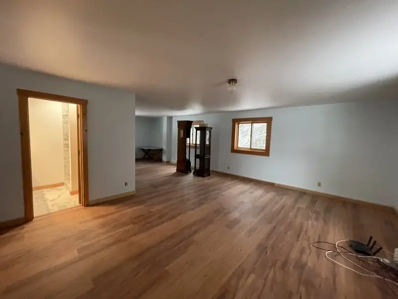 Open room with a new wood-look plank floor and a doorway to a tiled bathroom