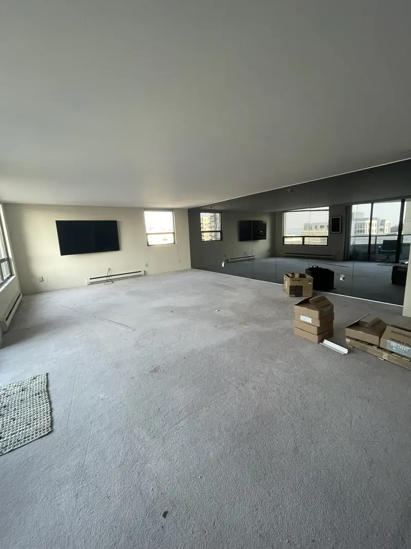 Condo living room cleared to concrete, looking toward the windows and the wall-mounted TV