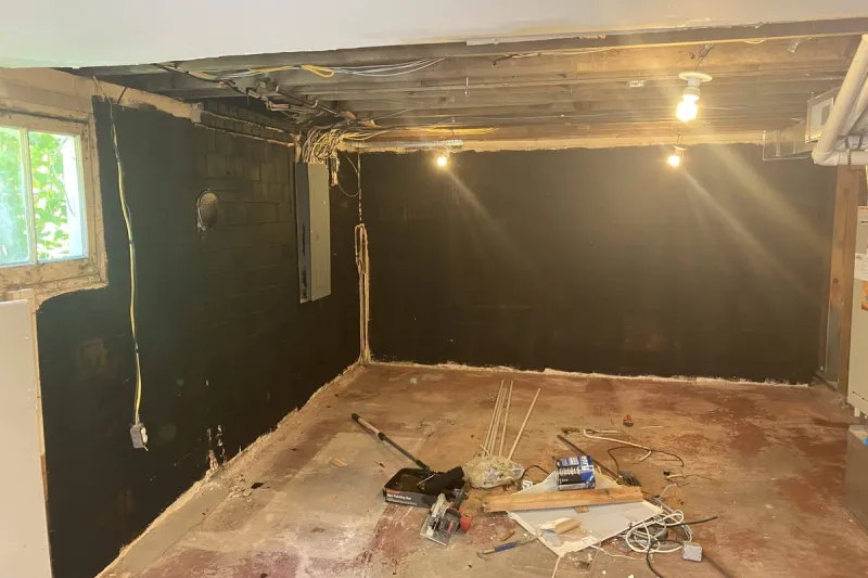 Concrete block foundation walls coated dark in a stripped basement before framing, Seattle, WA